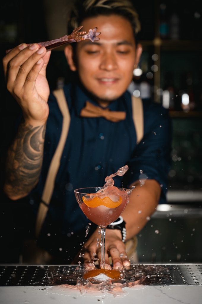 Bartender finishing a cocktail with a garnish
