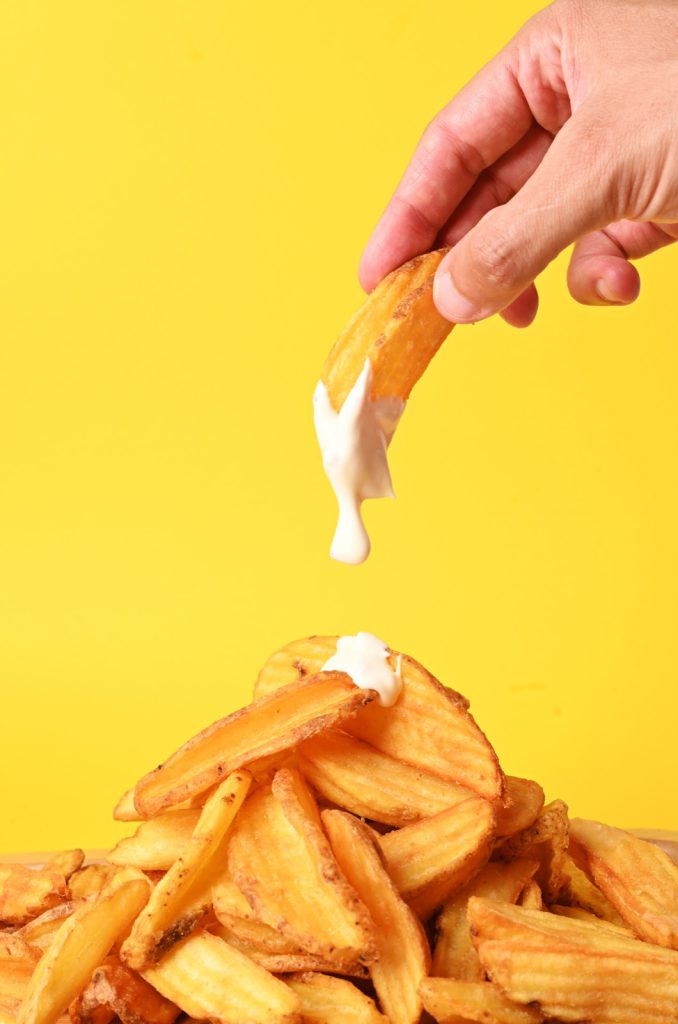 Fries dipped against a bright yellow backdrop