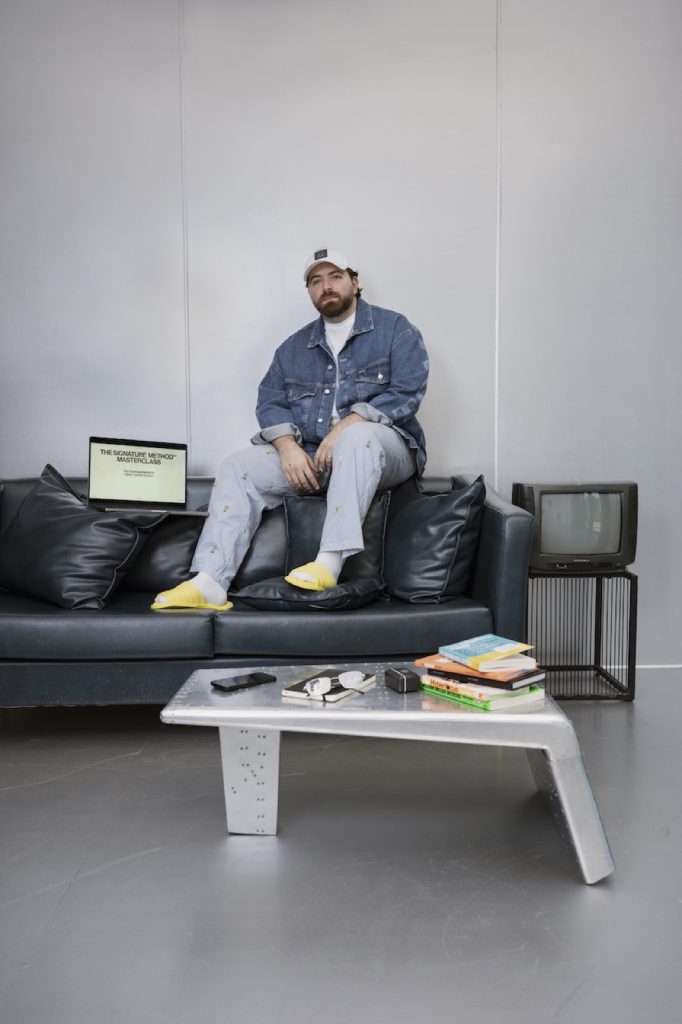 Creator in denim on a leather sofa with laptop